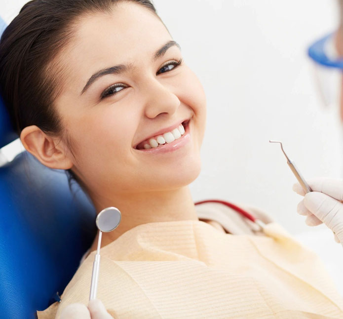 A woman sitting in the dentist chair holding a tooth brush.